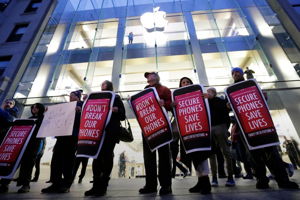 Protesters carry placards outside an Apple store in Boston, Feb. 23, 2016. (Photo by Steven Senne/AP)