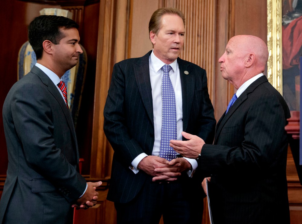 FILE - In this Sept. 27, 2017, file photo, from left, Rep. Carlos Curbelo, R-Fla., Rep. Vern Buchanan, R-Fla., and House Ways and Means Committee Chairman Kevin Brady, R-Texas, confer before a news conference at the Capitol in Washington.