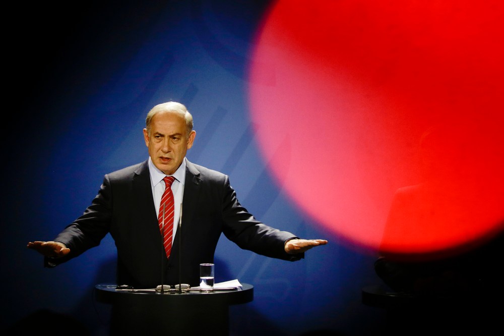 Seen through the silhouette of a cameraman, Israeli Prime Minister Benjamin Netanyahu speaks at a news conference with German Chancellor Angela Merkel during a meeting at the chancellery in Berlin, Oct. 21, 2015. (Photo by Markus Schreiber/AP)
