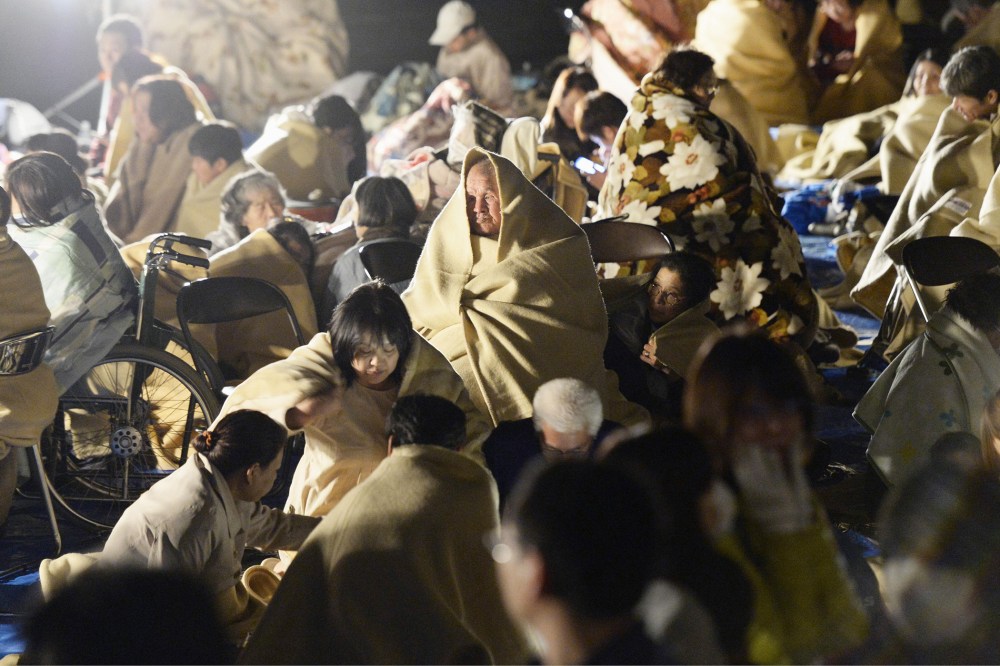 Residents wrap themselves in blankets as they take shelter outside the town hall of Mashiki, near Kumamoto city, southern Japan, after the earthquake early April 15, 2016. (Photo by Ryosuke Uematsu/Kyodo News/AP)