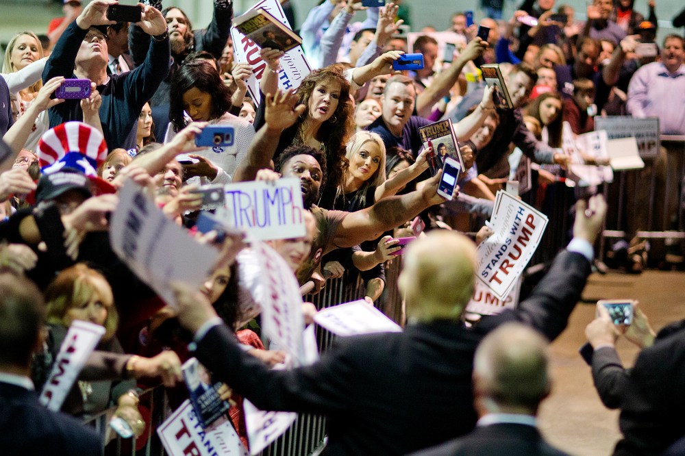 Audience members cheer as Republican presidential candidate Donald Trump signs autographs at a campaign event, Feb. 21, 2016, in Atlanta, Ga. (Photo by David Goldman/AP)