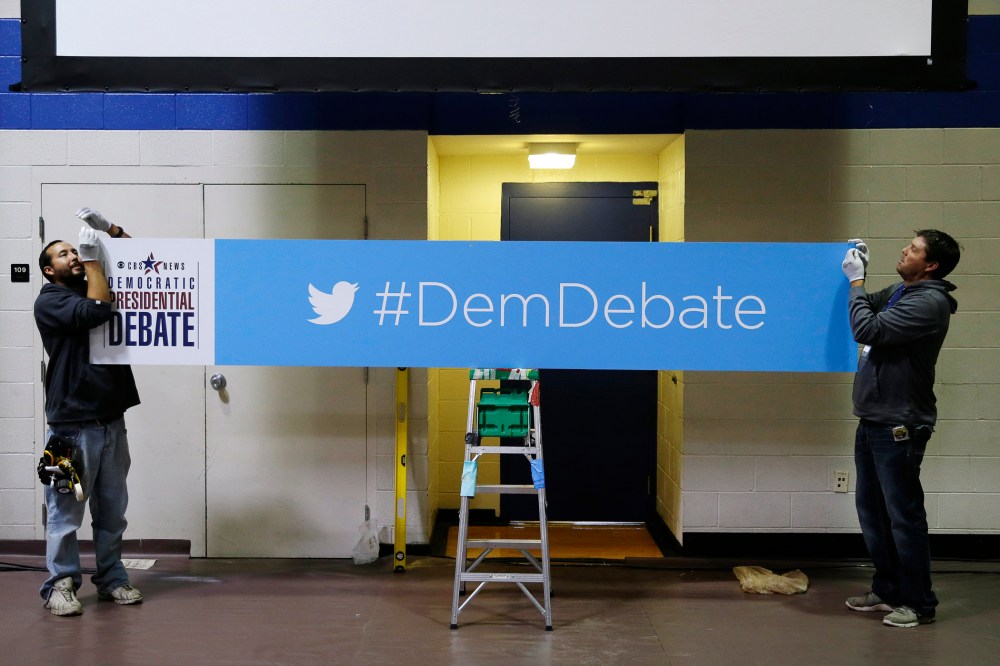 Workers Daniel Rodriguez, left, and Chad Parson hang a sign in the media filing center before Saturday night's Democratic Presidential Debate, Nov. 13, 2015, in Des Moines, Iowa. (Photo by Charlie Neibergall/AP)