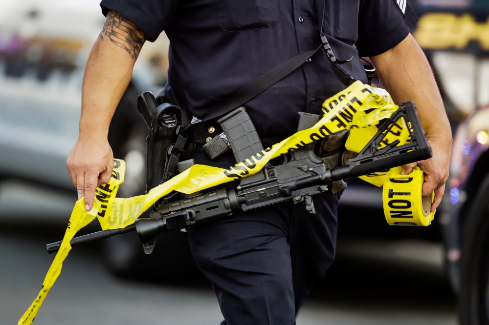 A police officer deploys tape to an area near where authorities stopped a vehicle in San Bernardino, Calif., Dec. 2, 2015. (Photo by Damian Dovarganes/AP)
