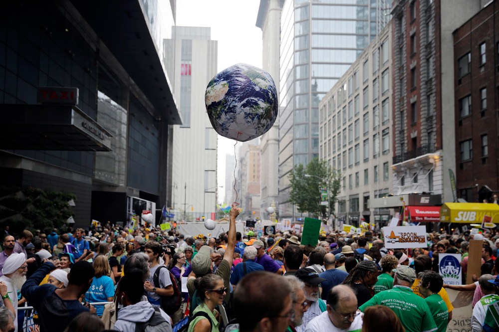 A man holds an earth balloon into the air as people fill the street before a global warming march in New York Sunday, Sept. 21, 2014. (Photo by Mel Evans/AP)
