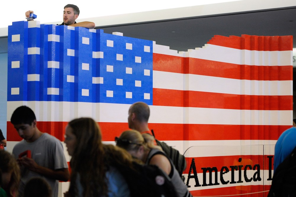LEGO master builder Chris Steininger places a brick while building the world's largest LEGO American flag to celebrate the opening of the Innovation Wing at the National Museum of American History (Photo by Steve Ruark/AP).