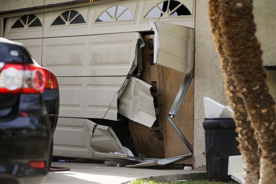A garage door of Enrique Marquez's home is seen broken in a recent FBI raid, Wednesday, Dec. 9, 2015, in Riverside, Calif. (Photo by Jae C. Hong/AP)