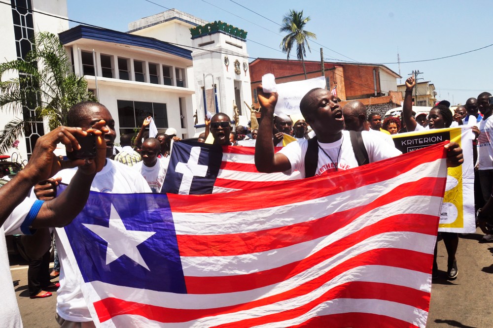 People march with a Liberian flag as they celebrate Liberia being an Ebola free nation in Monrovia, Liberia, Monday, May 11, 2015. (Photo by Abbas Dulleh/AP)