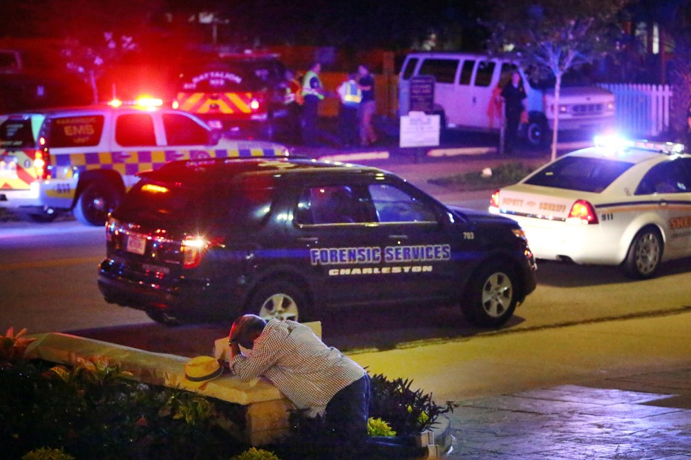 A man kneels across the street from where police gather outside the Emanuel AME Church following a shooting, June 17, 2015, in Charleston, S.C. (Photo by Wade Spees/The Post And Courier/AP)