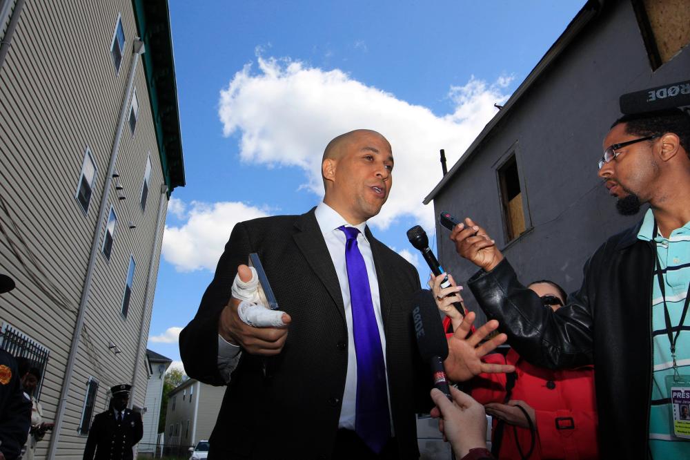 Newark Mayor Cory Booker, hand bandaged, talking outside his home the morning after he rescued a next-door neighbor from a fire.