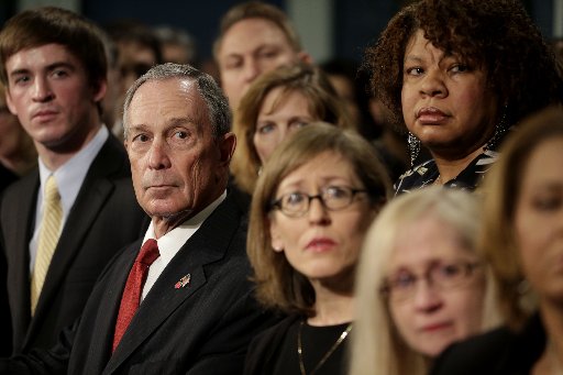 New York City Mayor Michael Bloomberg, second from left, watches a video testimonial surrounded by shooting survivors and victims' relatives during a news conference in City Hall in New York, Monday, Dec. 17, 2012.  Bloomberg and dozens of shooting...