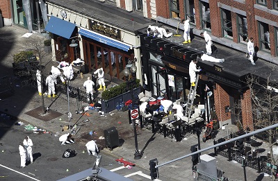 Investigators comb through the scene of one of the blast sites of the Boston Marathon explosions on April 17, 2013. (Photo by Julio Cortez/AP)