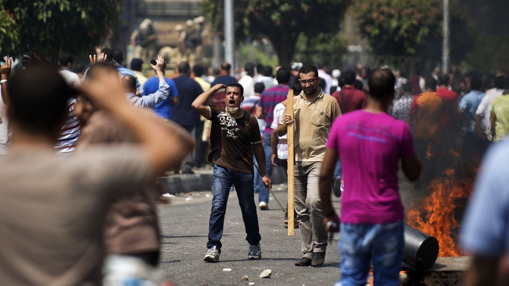 Supporters of ousted president Mohamed Morsi clash with Egyptian riot police on a street leading to Rabaa al-Adawiya square in Cairo on August 14, 2013 as security forces backed by bulldozers moved in on two huge pro-Morsi protest camps, launching a...