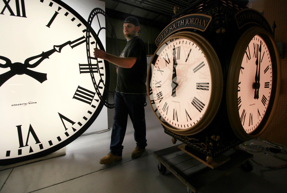 In this Thursday, Nov. 3, 2011 photo, Dan LaMoore of Electric Time Company moves a clock face at their plant in Medfield, Mass.