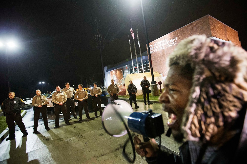 Protester Derrick Robinson shouts through a bullhorn at police officers standing guard during a demonstration outside the Ferguson Police Department on Nov. 23, 2014, in Ferguson, Mo. (David Goldman/AP)