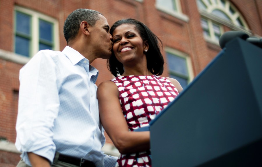 President Barack Obama (L) kisses First Lady Michelle Obama (R) as they arrive to deliver remarks during a campaign event in Dubuque, Iowa, on Aug. 15, 2012, during his three-day campaign bus tour across the state. (Photo by Jim Watson/AFP/Getty)