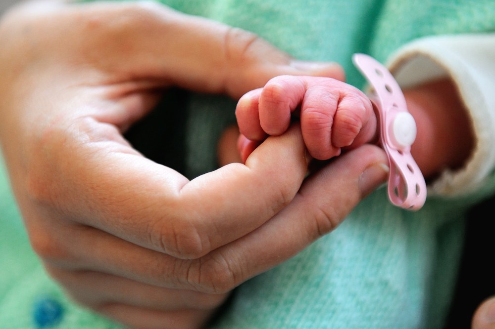 A new born baby takes the finger of his mother after the delivery. (Photo by Philippe Huguen/AFP/Getty)