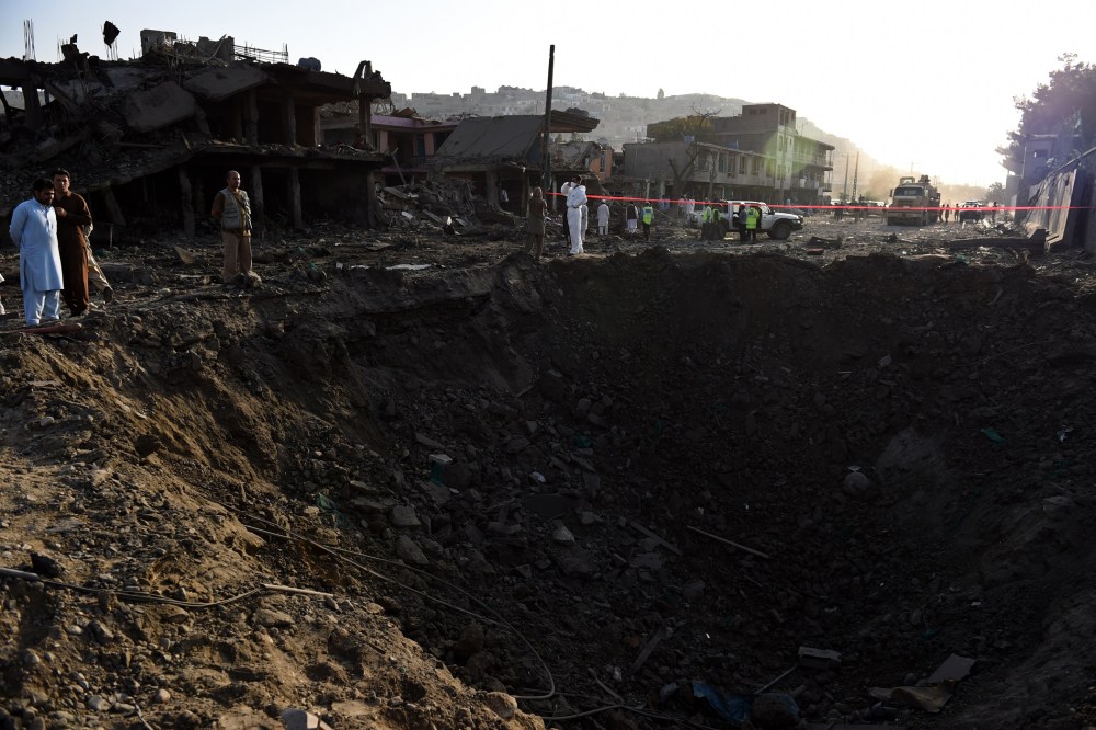 Afghan security forces and residents stand near the crater from a powerful truck bomb in Kabul on Aug. 7, 2015. (Photo by Wakil Kohsar/AFP/Getty)
