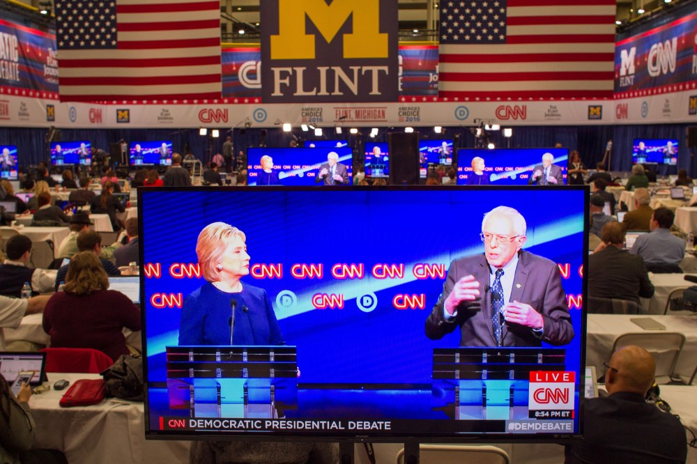 Journalists watch Democratic presidential candidates Hillary Clinton and Bernie Sanders debate on televisions in the media room at the University of Michigan in Flint, Mich. on March 6, 2016. (Photo by Geoff Robins/AFP/Getty)