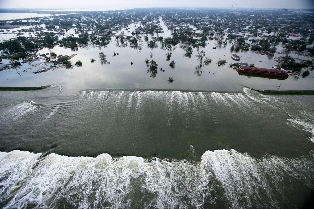 Water spills over a levee along the Inner Harbor Navigational Canal in the aftermath of Hurricane Katrina on Aug. 30, 2005 in New Orleans, La. (Photo by AFP/Getty)