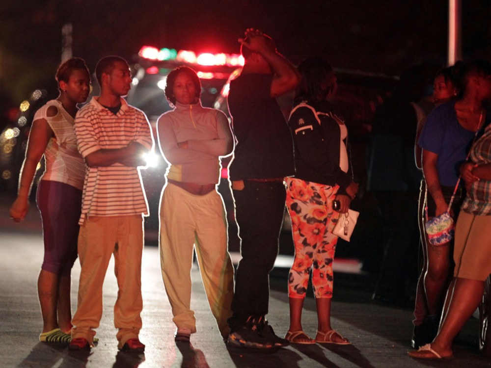 People gather in the 5100 block of S. Wood St. after multiple shooting victims are attended to and moved to waiting ambulances near Cornell Square Park in the Back of the Yards neighborhood of Chicago, September 19, 2013.