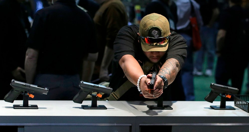 Firearms buyer Joshua Asperila checks out various Glock hand guns on display during the Shooting Hunting and Outdoor Trade Show,  Tuesday, Jan. 14, 2014, in Las Vegas.