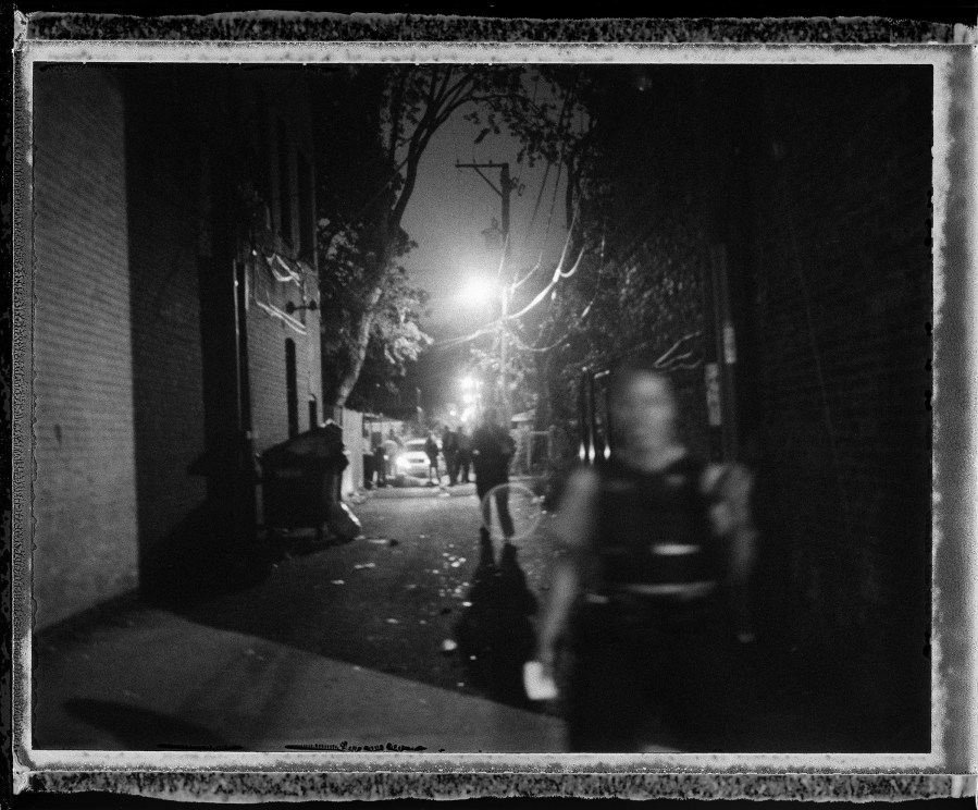 Minutes after a double shooting, a man lies in an alley in the Grand Crossing neighborhood of Chicago's South Side.