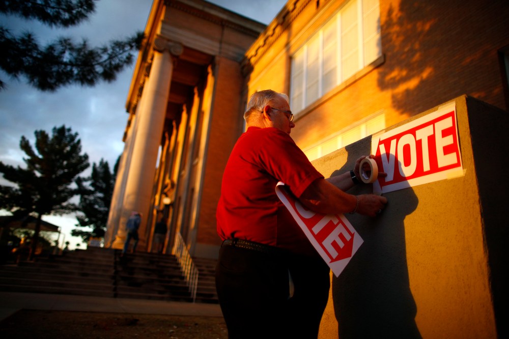 A poll worker posts signs at a polling station, Feb. 28, 2012, in Phoenix, Ariz.