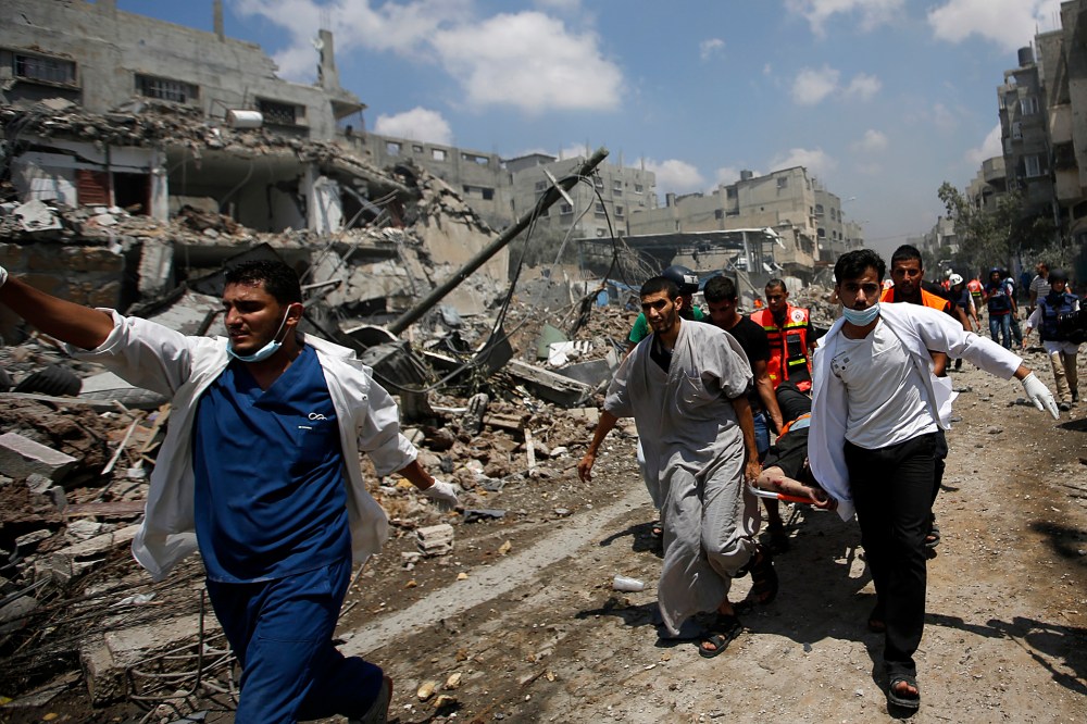 Palestinian paramedics lift the body of a man from the Al Shejaeiya neighborhood, during a brief period of ceasefire requested by local rescue forces to retrieve dead and wounded from the Shuja'iyya neighborhood in east Gaza City, July 20, 2014.