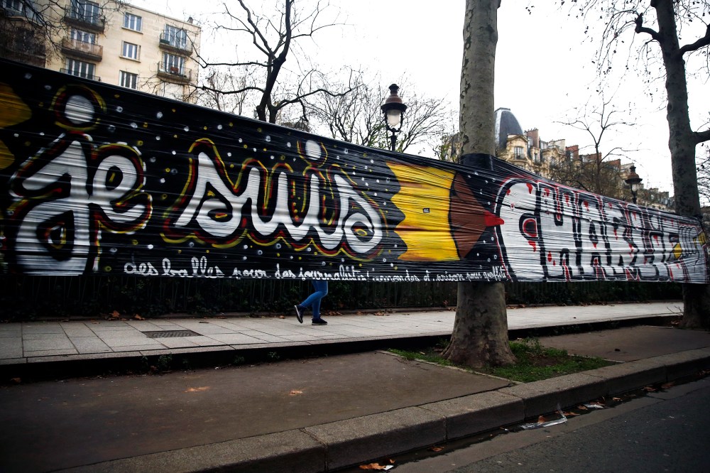 A woman walks behind a large banner stating 'Je suis Charlie' that is hung between trees next the 'Charlie Hebdo' offices in Paris, France, on Jan. 12, 2015. (Photo by Etienne Laurent/EPA)