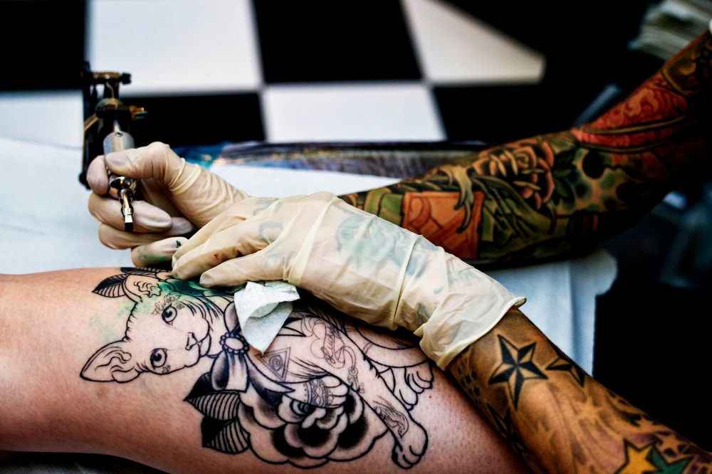 A tattoo artist works on a client at the The Family Business Tattoo parlor.