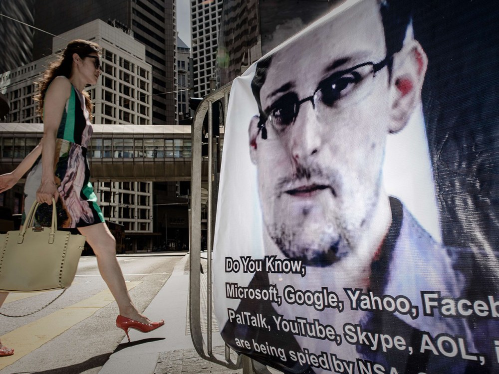 This file picture taken on June 18, 2013 shows a woman walking past a banner displayed in support of former US spy Edward Snowden in Hong Kong.  (Photo by Philippe Lopez/AFP/Getty Images)