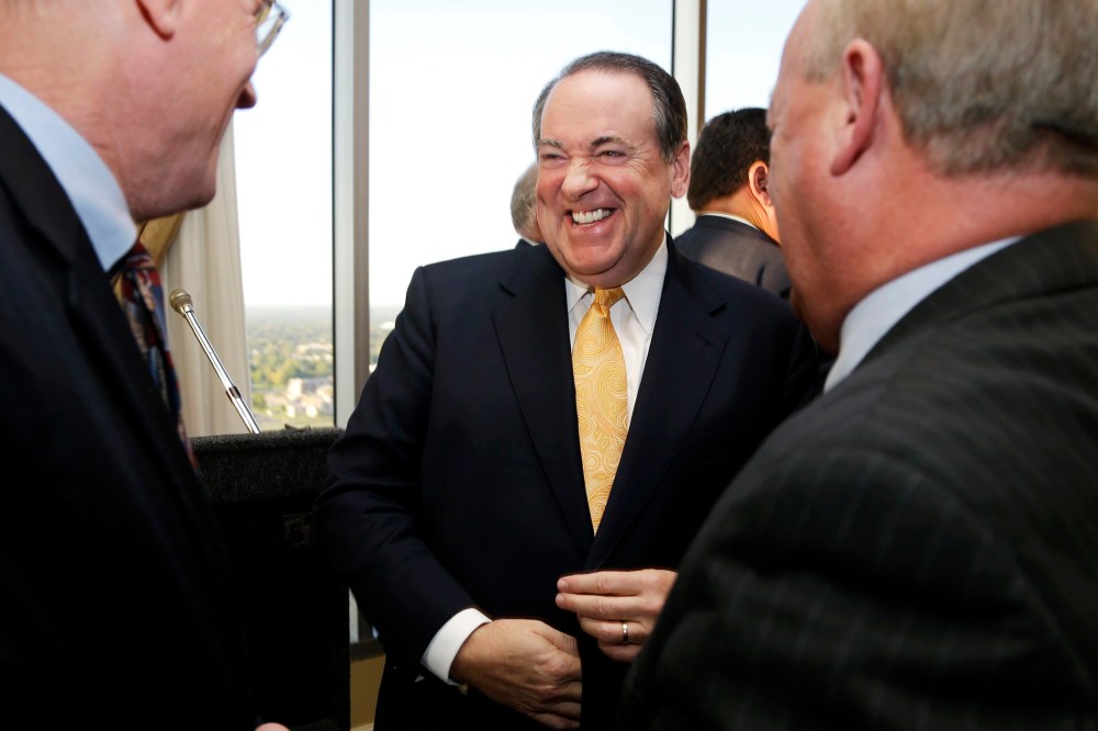 Former Arkansas Gov. Mike Huckabee laughs as he is greeted after a meeting of the Political Animals Club in Little Rock, Ark., Oct. 25, 2013.