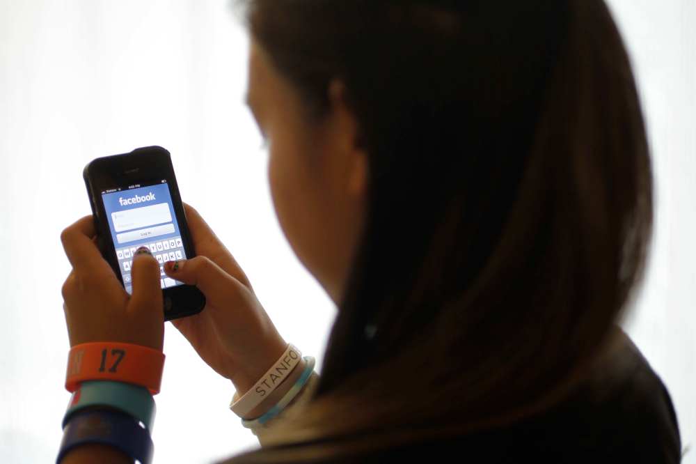 An unidentified 11-year-old girl logs into Facebook on her iPhone at her home in Palo Alto, Calif. in 2012. (AP Photo/Paul Sakuma)