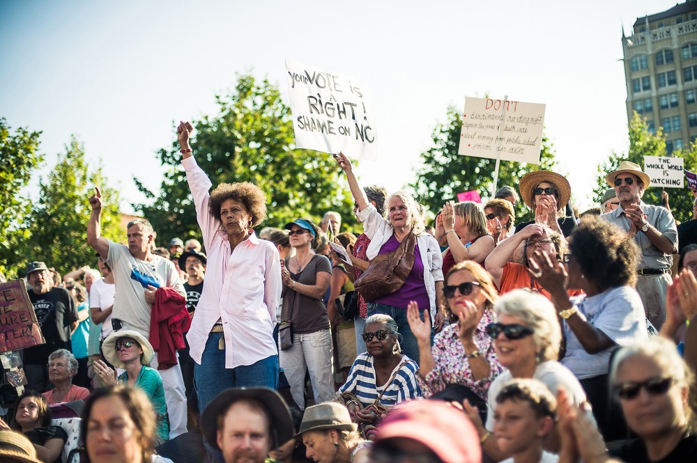 A crowd cheer in support during a speech by Rev Dr. William Barber II, president of the North Carolina NAACP in Asheville, NC's Pack Square Park during Mountain Moral Monday on Aug 5, 2013.