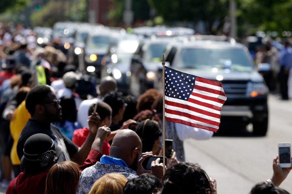 A mourner holds an American flag as the funeral procession for Muhammad Ali makes its way down Muhammad Ali Boulevard in Louisville, Ky. on June 10, 2016. (Photo by Michael Conroy/AP)