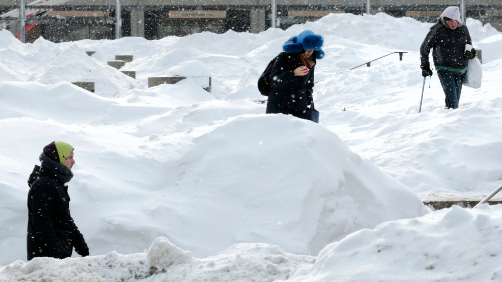 As snow flurries begin to fall again, pedestrians walk through Boston City Hall Plaza in Boston, on Feb. 17, 2015. (Photo by Charles Krupa/AP)