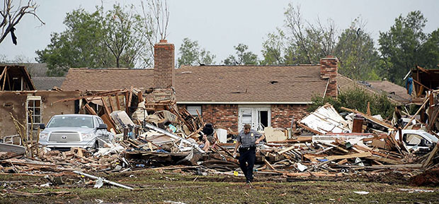 A law enforcement official stands in the yard of a damaged home after a tornado struck Moore, Oklahoma, May 20, 2013. A 2-mile-wide (3-km-wide) tornado tore through the Oklahoma City suburb of Moore on Monday, killing at least 51 people while...