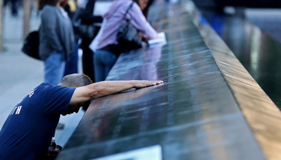 Joe Torres of Sayreville, New Jersey, a fire captain from Elizabeth, New Jersey, kneels as he touches the name of his sister-in-law Krystine Bordenabe during memorial ceremonies for the eleventh anniversary of the terrorist attacks on lower Manhattan...