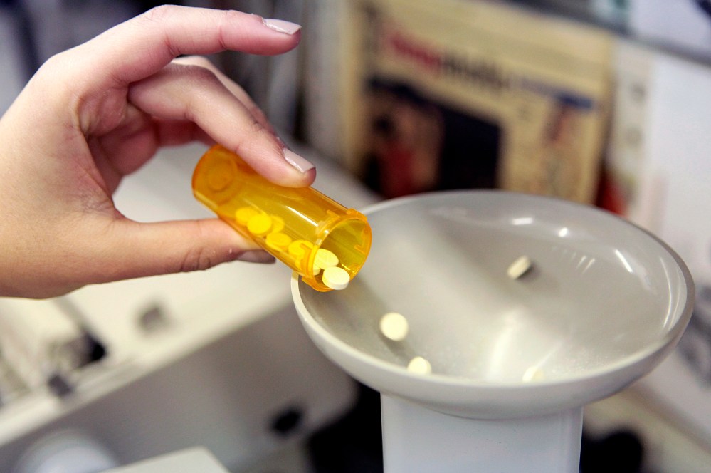 A pharmacy employee dumps pills into a pill counting machine as she fills a prescription while working at a pharmacy in New York