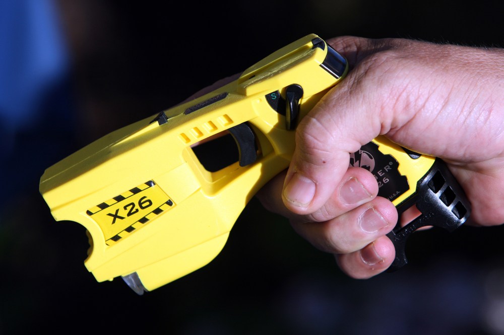 A police officer poses with a taser. (Photo by Sebastien Nogier/Reuters)