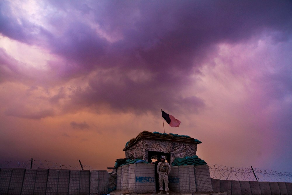 A U.S. Marine from the First Battalion Eighth Marines Alpha Company looks out as an evening storm gathers above an outpost near Kunjak in southern Afghanistan's Helmand province, Feb. 22, 2011. (Photo by Finbarr O'Reilly/Reuters)