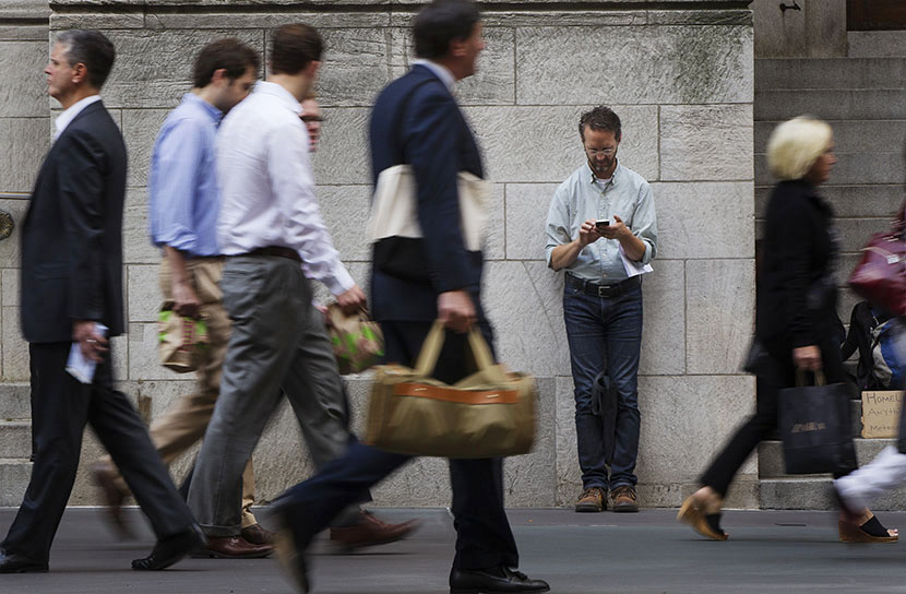 A man stops to lean against a building as pedestrians walk past while he looks down at his cell phone on 5th Avenue in New York, NY. (Photo by Lucas Jackson/Reuters)