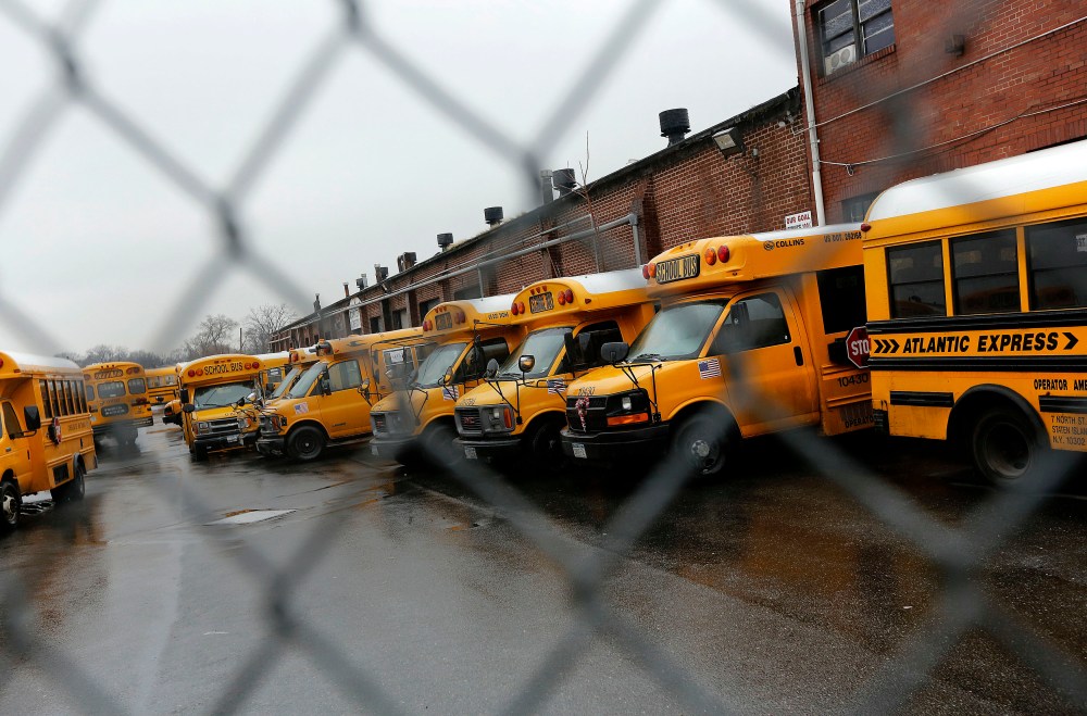 School buses are seen parked behind a locked bus depot fence in the Queens borough of New York Jan. 16, 2013. (Photo by Shannon Stapleton/Reuters)