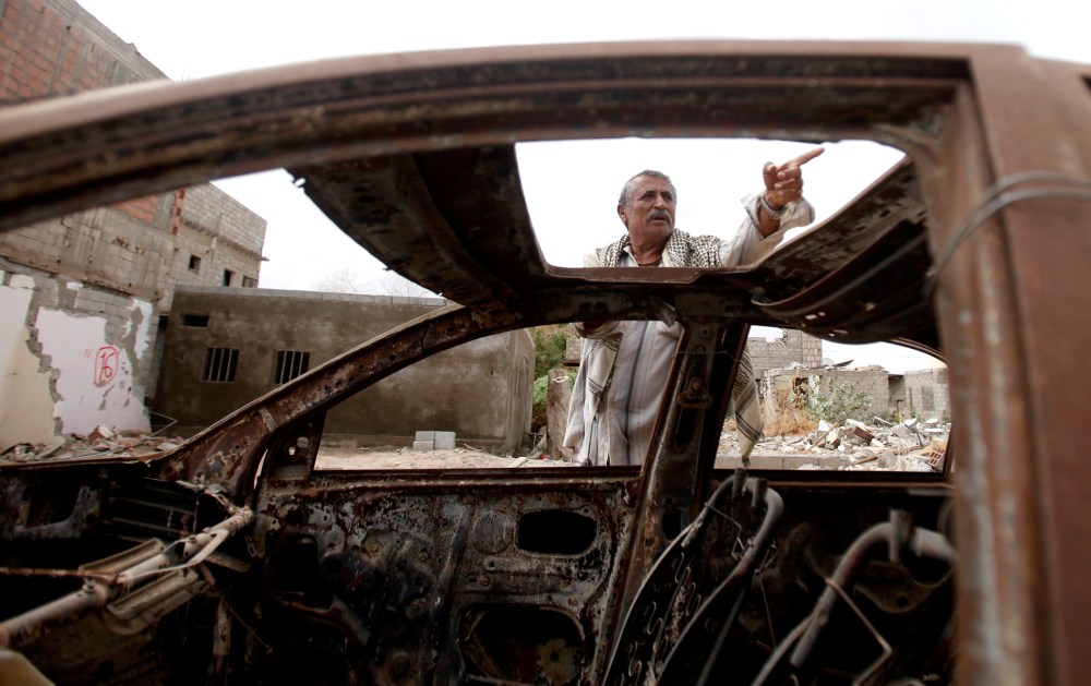 Muhammad Saleh Abdullah, 65, a resident of the southern Yemeni town of Jaar, gestures as he stands near his car destroyed by an air strike last year that was targeting al Qaeda-linked militants, in Jaar February 1, 2013