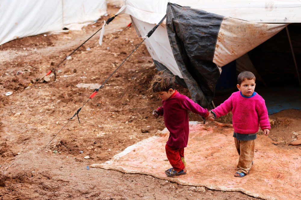 Syrian refugee children walk through mud at the Bab Al-Salam refugee camp in Azaz, near the Syrian-Turkish border, March 14, 2014.