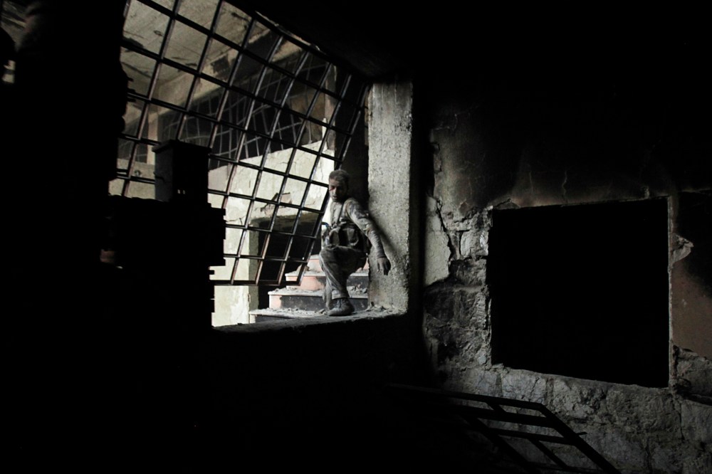 A wounded Islamist rebel fighter carries his weapon during what they said was a takeover of the Furn Al-Ali building that was under control by the Syrian regime in Ramouseh