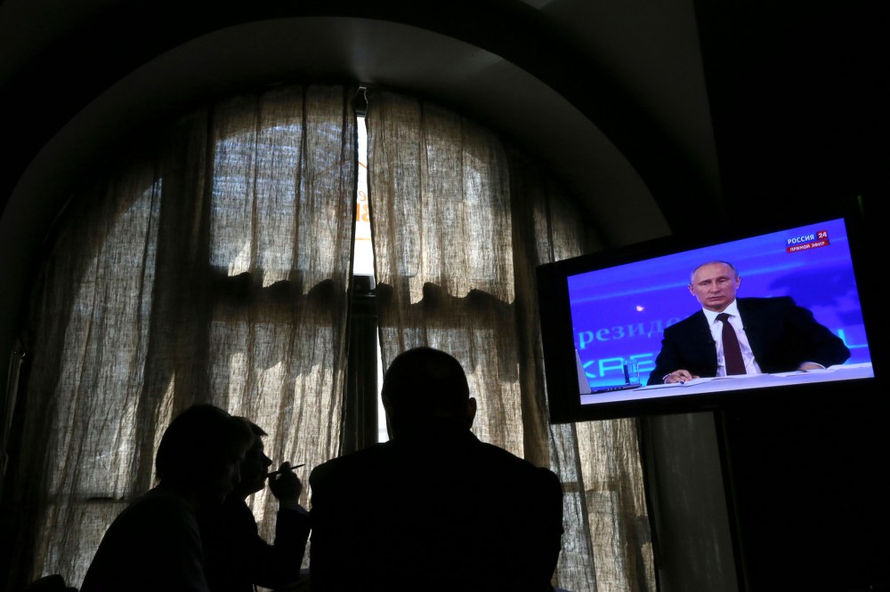 People look at a screen at a media centre during Russian President Vladimir Putin's live broadcast in Moscow on April 17, 2014.