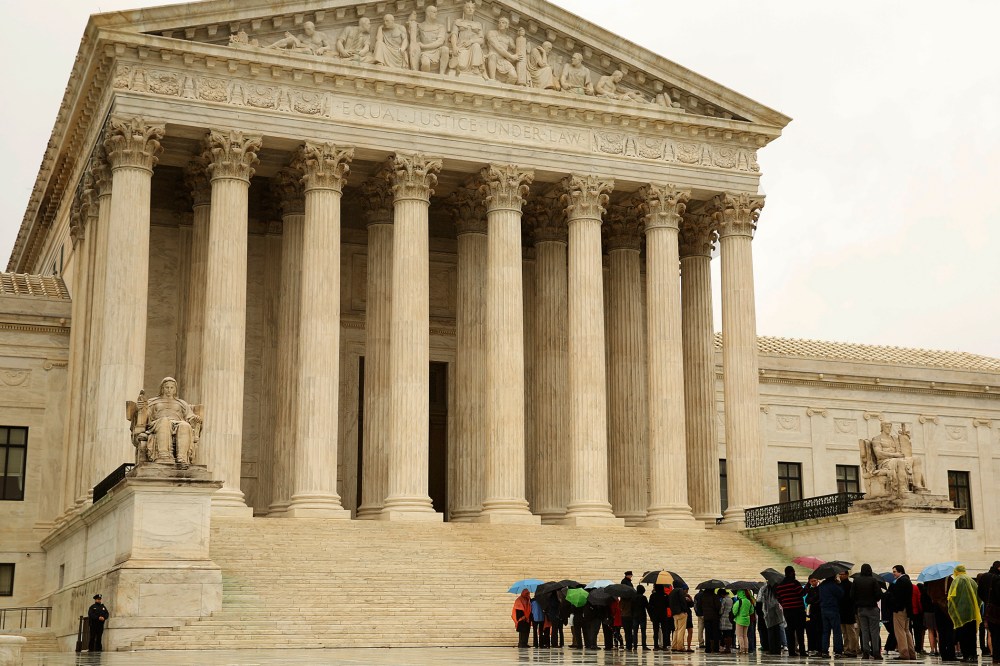 People line up in the rain outside of the U.S. Supreme Court in Washington April 29, 2014.