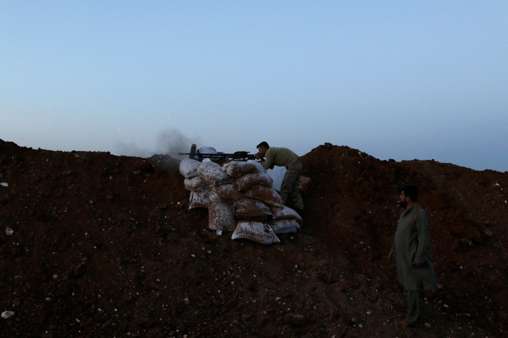A rebel fighter takes a position as he fires his weapon towards forces loyal to Syria's President Bashar al-Assad who are stationed in Wadi al-Deif military camp in Idlib province June 1, 2014.
