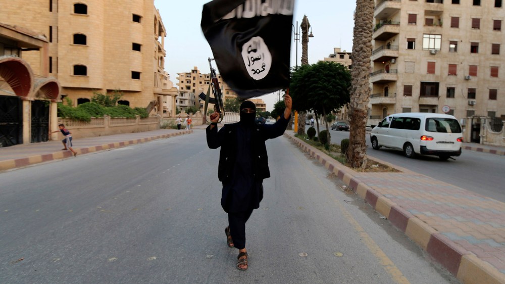 A member loyal to the Islamic State in Iraq and the Levant (ISIL) waves an ISIL flag in Raqqa June 29, 2014.